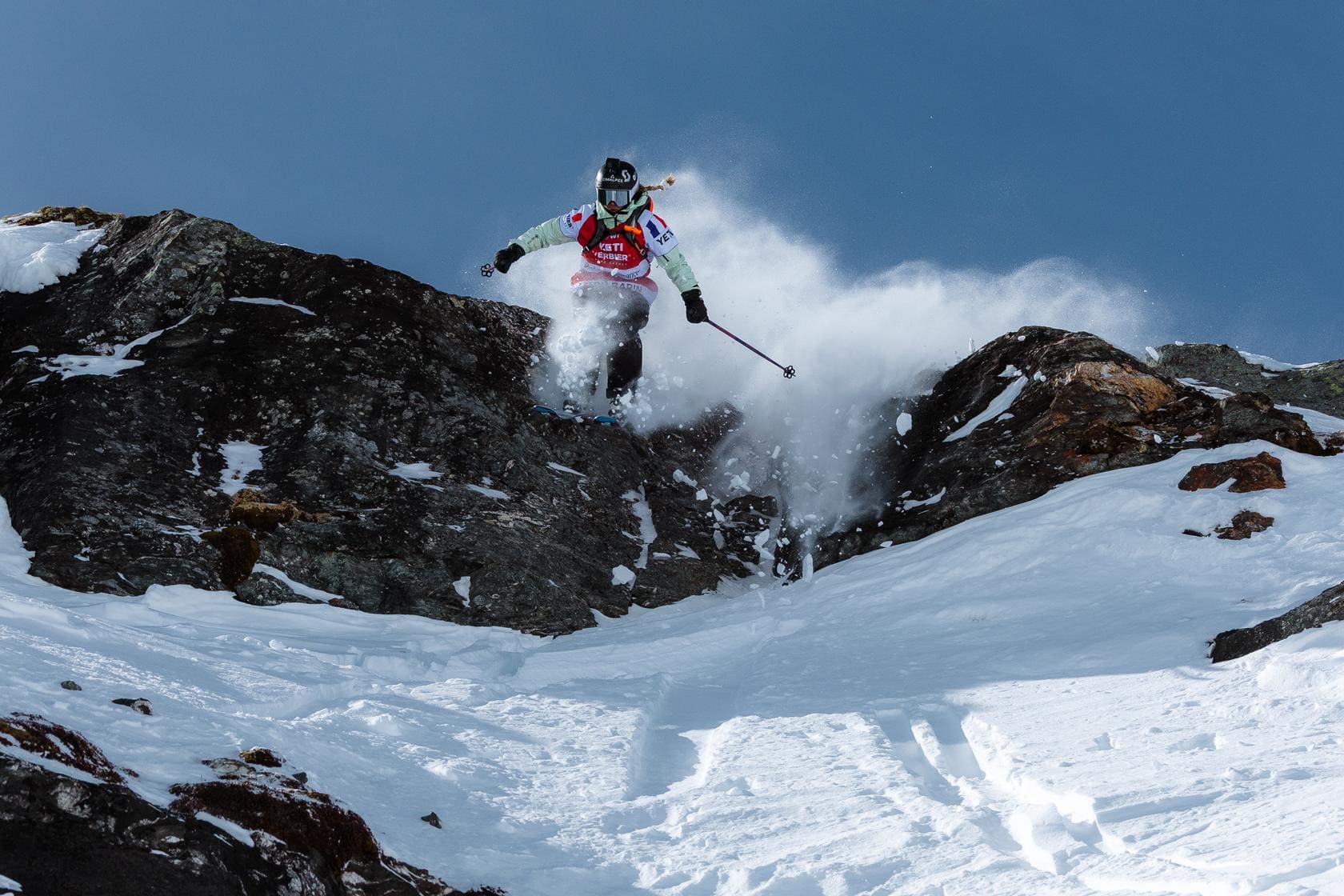 Rider de freeride saltando una línea de roca y nieve durante el Freeride World Tour